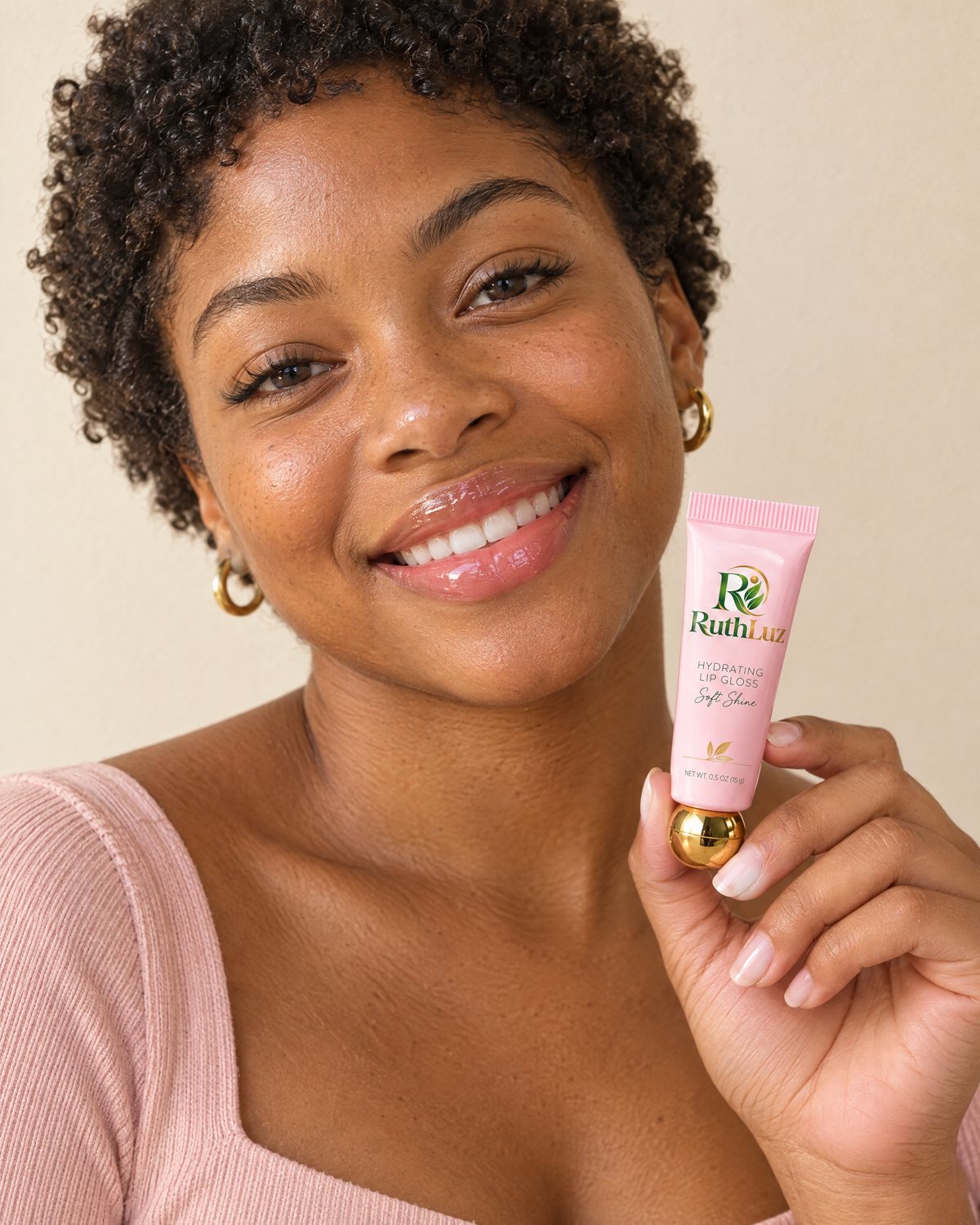A woman smiling, holding the RuthLuz Hydrating Lip Gloss tube